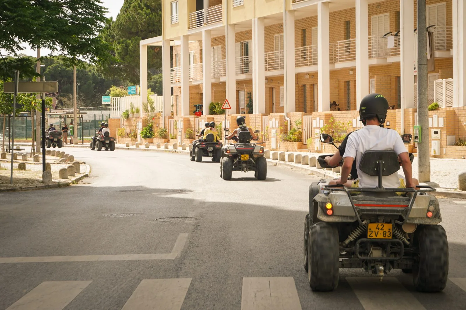 Group of quads riding through a sunny Costa da Caparica street